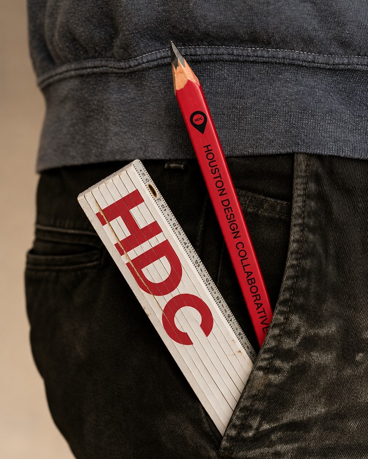 A Houston Design Collaborative branded pencil and folding ruler tucked into a back pocket.